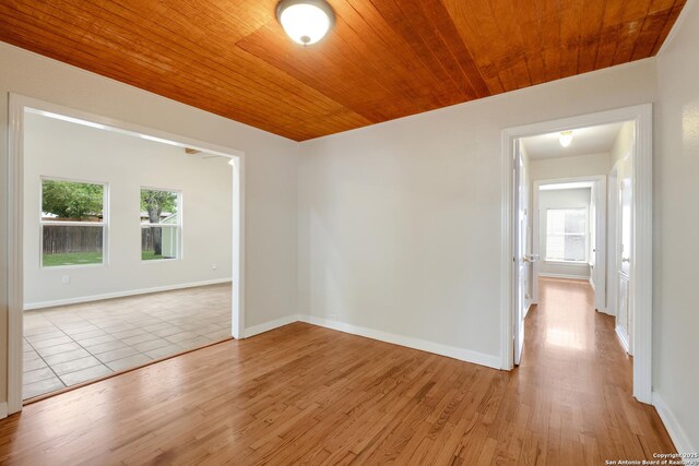spare room featuring wood ceiling, light wood-type flooring, and baseboards