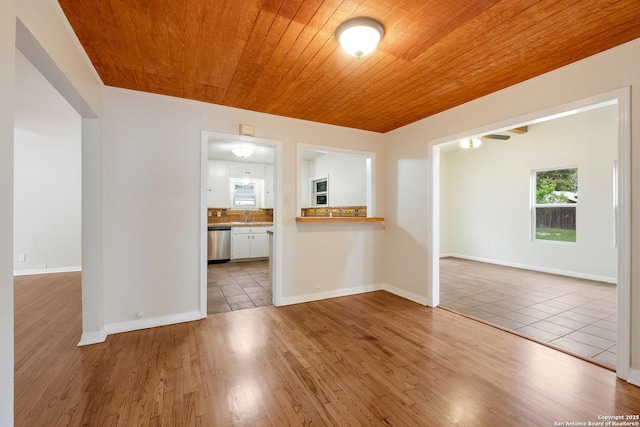 unfurnished room featuring a sink, wooden ceiling, and wood finished floors