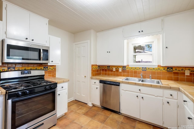 kitchen with appliances with stainless steel finishes, white cabinetry, decorative backsplash, and a sink