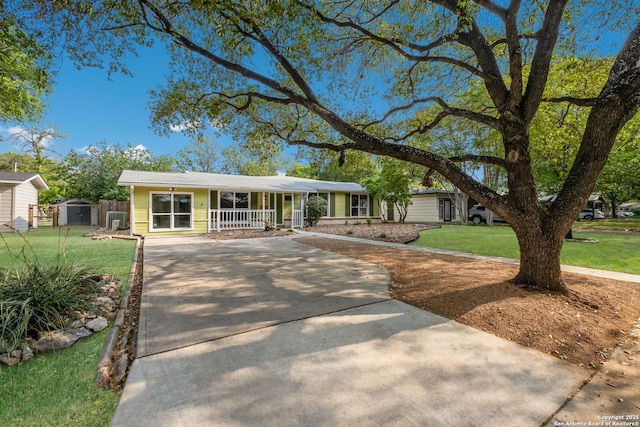 view of front facade featuring an outdoor structure, covered porch, a front lawn, a shed, and concrete driveway