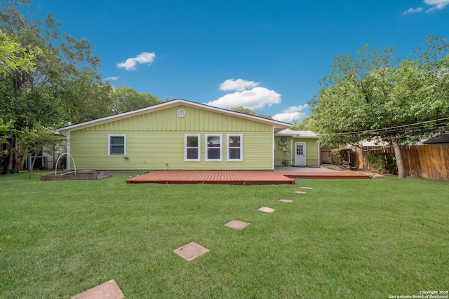 back of house with fence, a deck, and a lawn