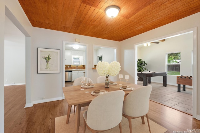 dining space featuring baseboards, light wood-style floors, and wood ceiling