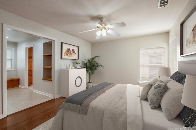 bedroom with a ceiling fan, visible vents, wood finished floors, and multiple windows