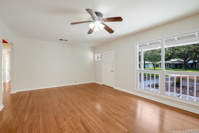 spare room featuring light wood finished floors, a ceiling fan, visible vents, and baseboards