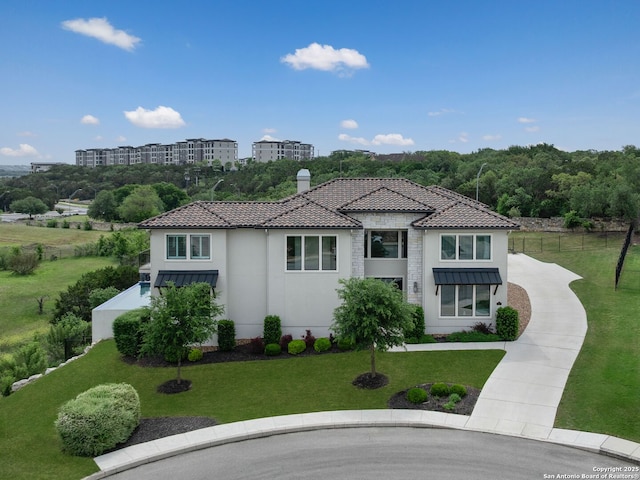 mediterranean / spanish house featuring stucco siding, a front lawn, and curved driveway