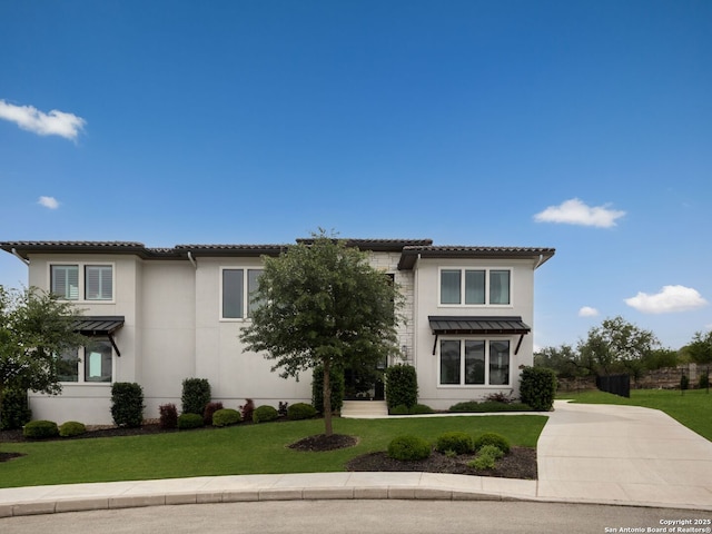 mediterranean / spanish home with a front lawn, a tile roof, concrete driveway, and stucco siding