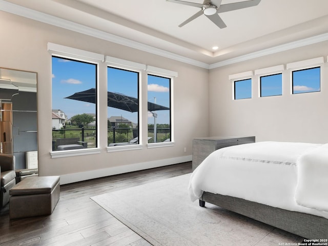 bedroom featuring wood finished floors, a ceiling fan, ornamental molding, and a raised ceiling