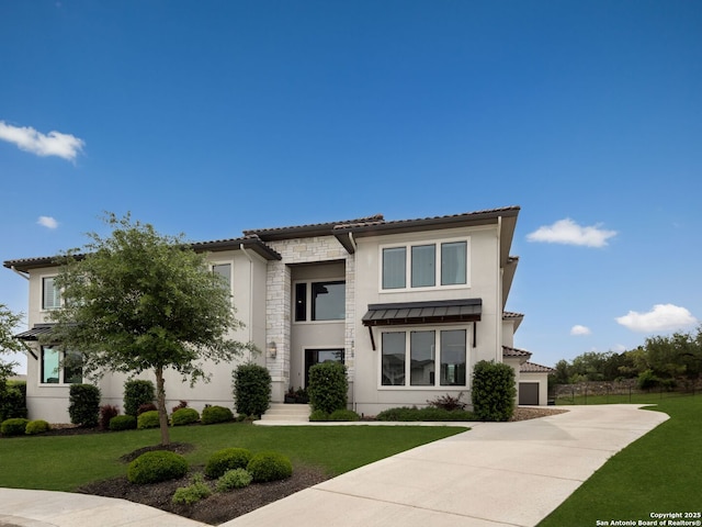 view of front of property with stucco siding, concrete driveway, a front lawn, and stone siding