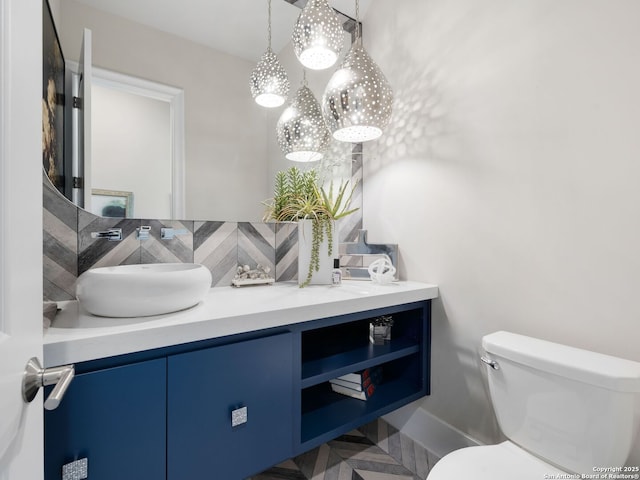 half bathroom featuring toilet, vanity, an inviting chandelier, and decorative backsplash