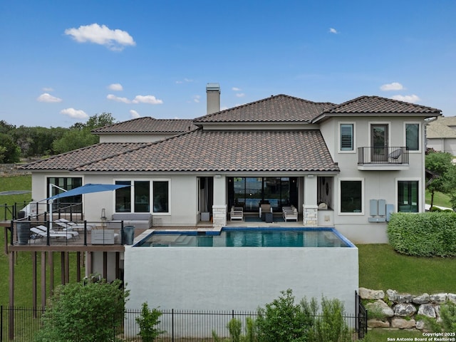 back of property featuring an outdoor living space, stucco siding, a fenced in pool, and a balcony