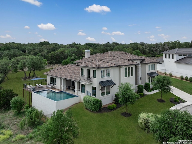 back of house featuring stucco siding, a yard, and a fenced in pool