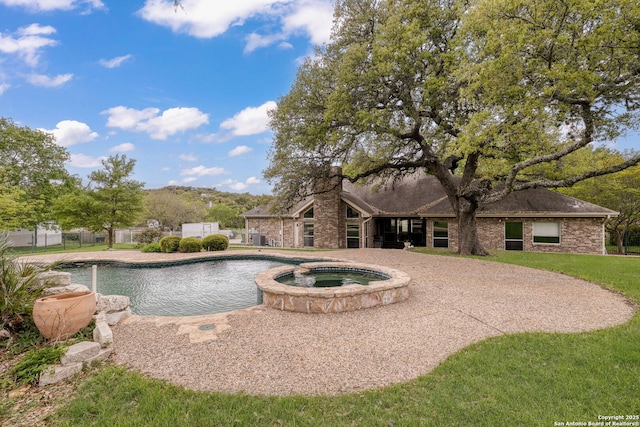 view of swimming pool with fence and a pool with connected hot tub