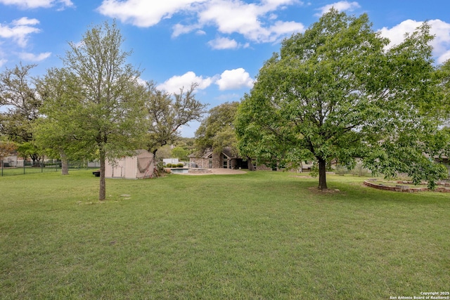 view of yard with fence, an outdoor structure, and a storage shed