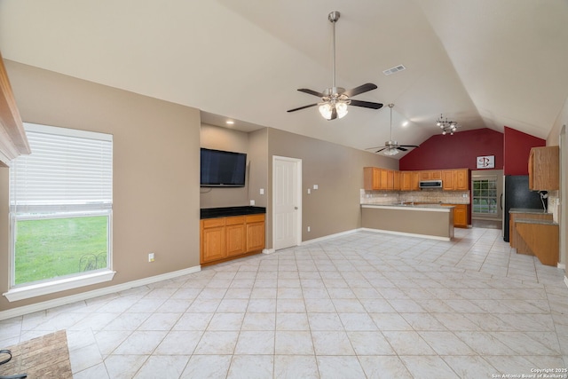 unfurnished living room with light tile patterned floors, a ceiling fan, visible vents, vaulted ceiling, and baseboards