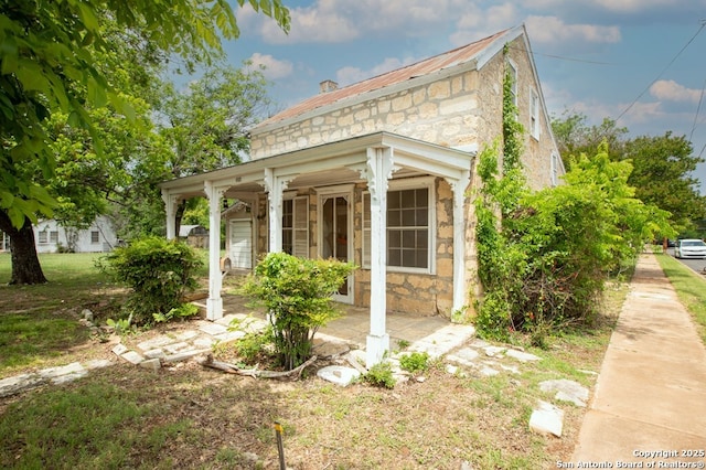 view of side of home with covered porch and stone siding
