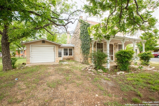 view of front facade with a chimney, stone siding, driveway, and an attached garage