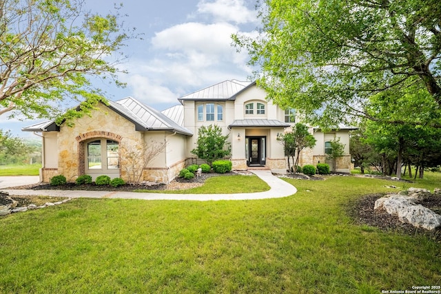 view of front facade with stucco siding, a standing seam roof, metal roof, stone siding, and a front lawn