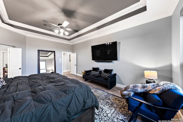 bedroom featuring ornamental molding, wood finished floors, a raised ceiling, and baseboards