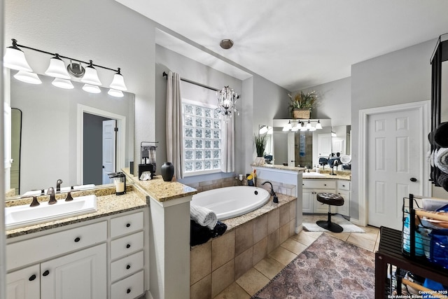 bathroom featuring tile patterned floors, two vanities, a garden tub, and a sink