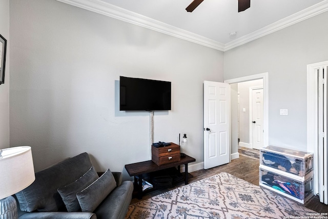 living area with crown molding, a ceiling fan, wood finished floors, and baseboards