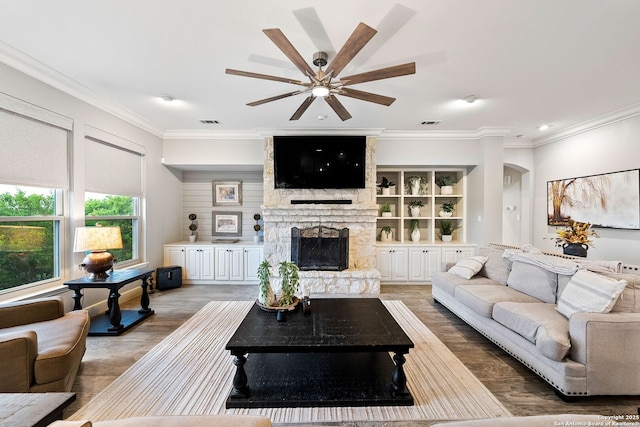 living area with a fireplace, wood finished floors, crown molding, and a ceiling fan