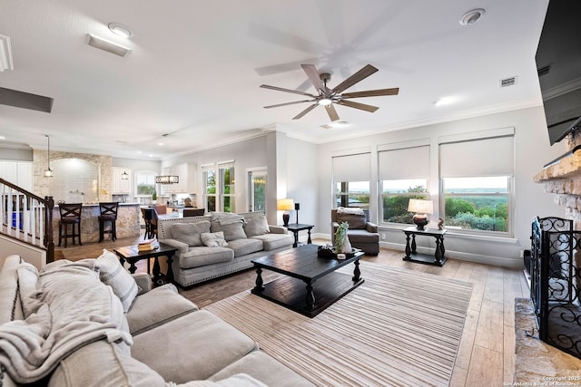 living area featuring a ceiling fan, a wealth of natural light, a fireplace, and light wood finished floors