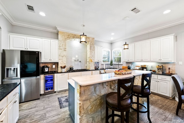kitchen featuring beverage cooler, visible vents, light wood-type flooring, and stainless steel fridge