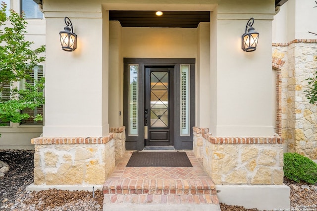 view of exterior entry with stucco siding and stone siding