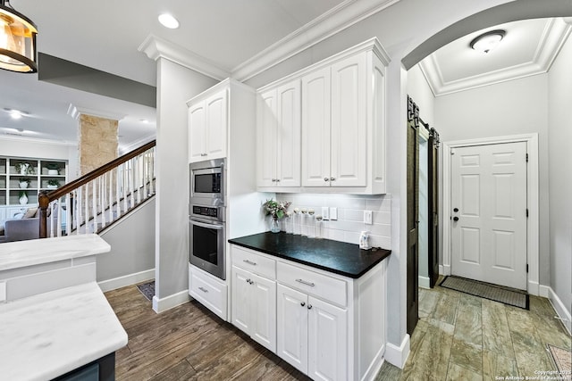 kitchen with white cabinetry, arched walkways, ornamental molding, and appliances with stainless steel finishes