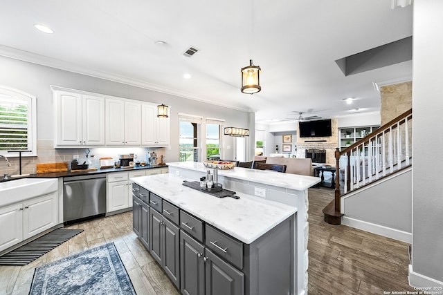 kitchen featuring white cabinetry, crown molding, stainless steel dishwasher, visible vents, and a kitchen island