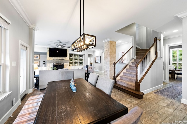 dining area featuring a fireplace, a ceiling fan, ornamental molding, and baseboards