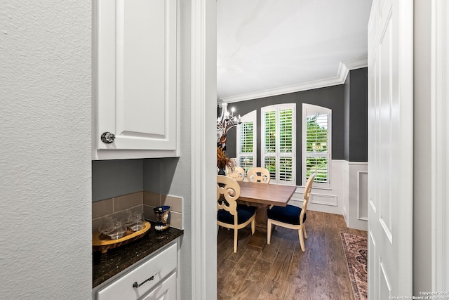 dining room featuring crown molding, dark wood-style floors, a wainscoted wall, and a textured wall