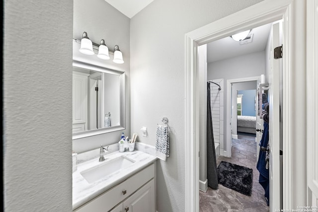 ensuite bathroom with ensuite bathroom, a textured wall, and vanity