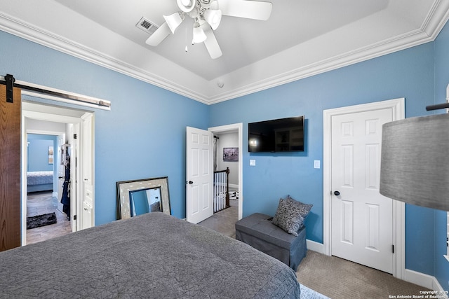 bedroom featuring a barn door, a raised ceiling, a ceiling fan, visible vents, and ornamental molding