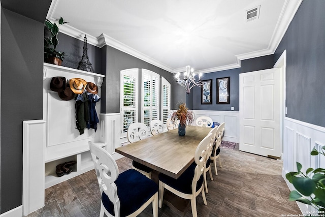 dining room with an inviting chandelier, visible vents, a decorative wall, and crown molding