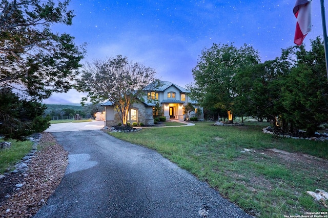 view of front of property with aphalt driveway, a front lawn, and stone siding
