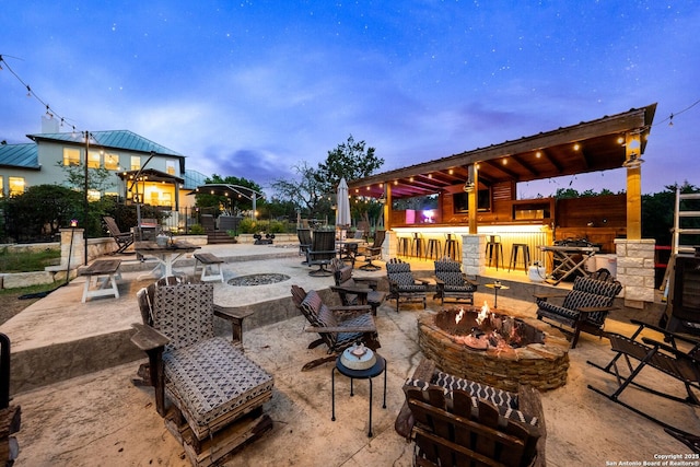 patio terrace at dusk with an outdoor fire pit and outdoor dry bar