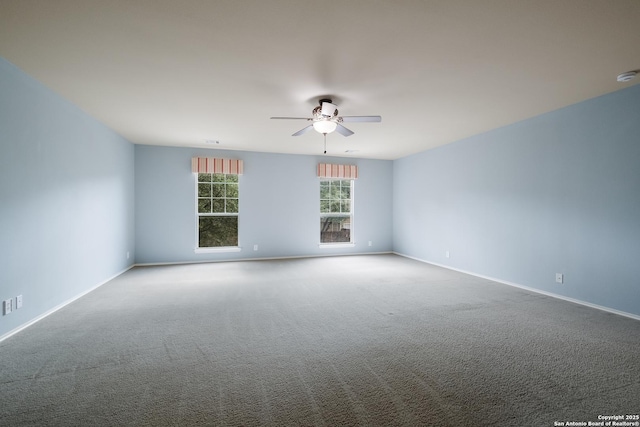 carpeted spare room with ceiling fan and baseboards