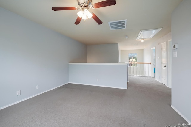 carpeted empty room featuring visible vents, ceiling fan with notable chandelier, and baseboards