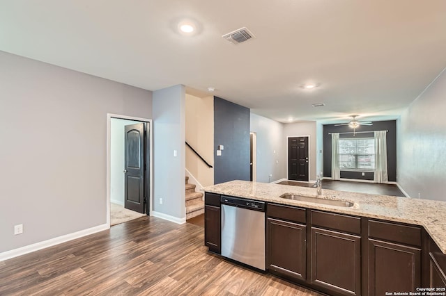 kitchen with dark brown cabinetry, wood finished floors, stainless steel dishwasher, a sink, and visible vents