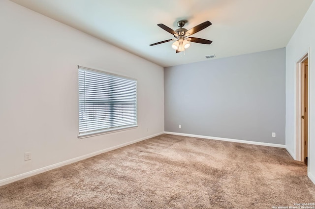 carpeted spare room featuring baseboards, visible vents, and ceiling fan