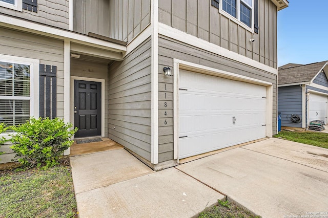 property entrance featuring a garage, board and batten siding, and driveway