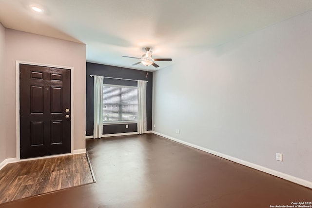 foyer entrance with ceiling fan, concrete flooring, and baseboards