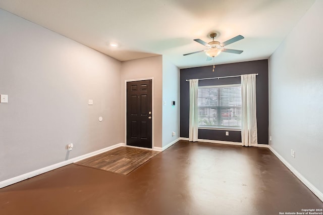 entrance foyer featuring ceiling fan, finished concrete flooring, and baseboards