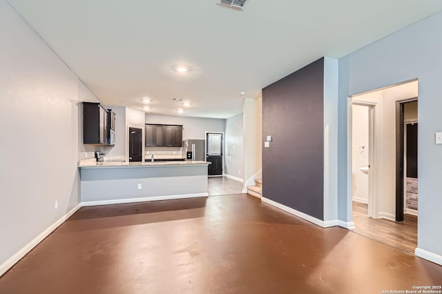 kitchen with recessed lighting, stainless steel appliances, concrete floors, baseboards, and a peninsula