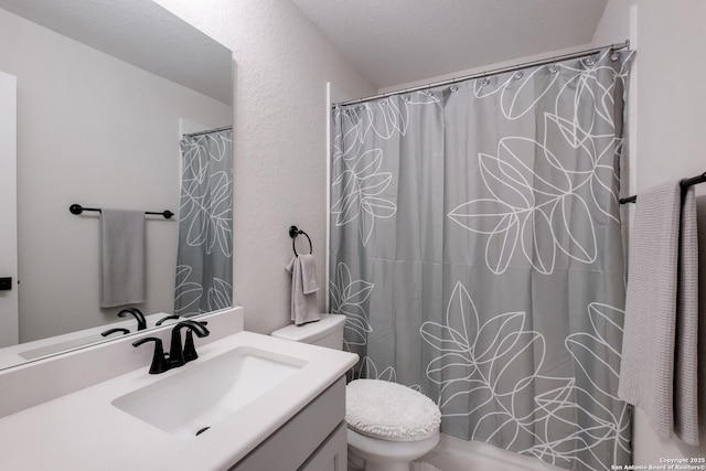full bathroom featuring toilet, curtained shower, a textured wall, and vanity