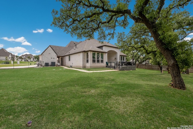back of house with a lawn, central AC, a fenced backyard, and brick siding