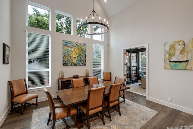 dining room with dark wood finished floors, a notable chandelier, high vaulted ceiling, and baseboards