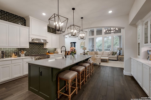 kitchen featuring a breakfast bar area, white cabinets, a notable chandelier, and wall chimney exhaust hood