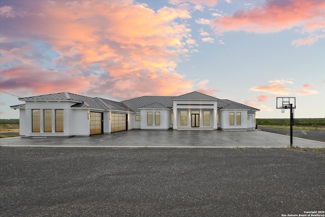 view of front facade with an attached garage, aphalt driveway, metal roof, and a standing seam roof